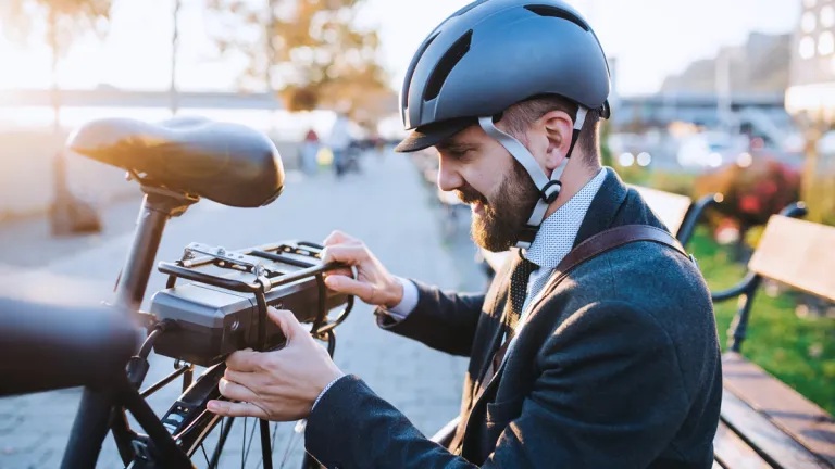 A rider removing a detachable e-bike battery for convenient charging, maintenance, and enhanced security