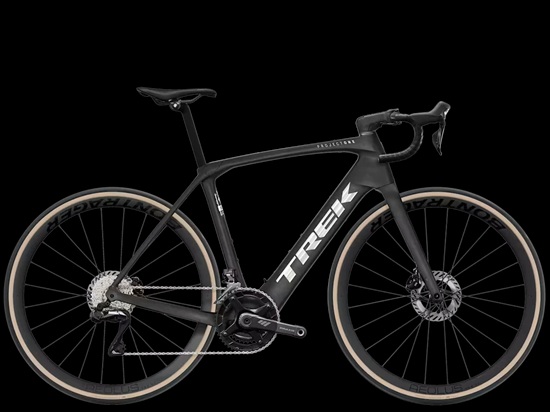 Black Trek road bicycle with drop handlebars, carbon wheels, disc brakes, and an electric motor system, shown in side profile on a black background.