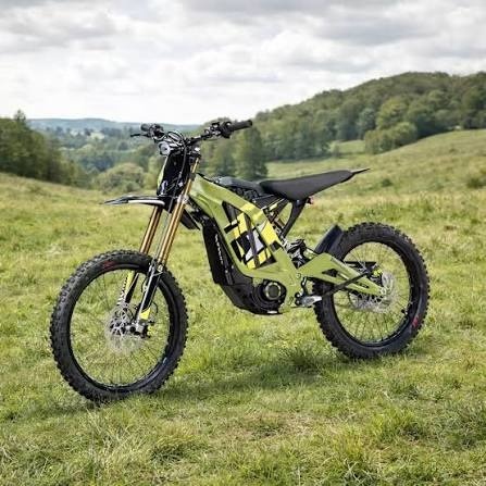 Olive green electric dirt bike parked on a grassy hillside under a cloudy sky.